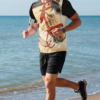 Man running on the beach wearing a jersey with an all over print of chinese horse art with black sleeves and red collar.